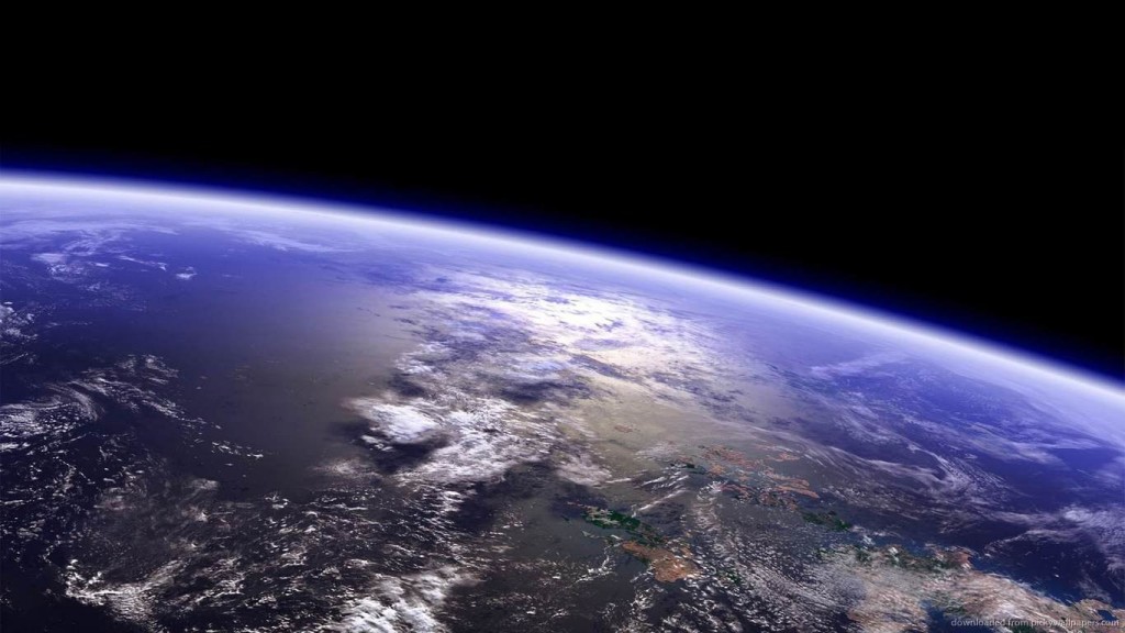 Photograph of earth in space with a close shot of a section of the earth with clouds, ocean, and land in view.